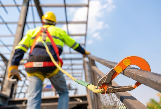 A construction worker working at height, Construction workers are working on steel roof trusses with Fall arrestor device for worker with hooks for safety body harness on the construction site.
